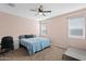 A bedroom has a ceiling fan, two windows that allow natural light to flow in, and neutral-colored carpet at 7749 W Florence Ave, Phoenix, AZ 85043
