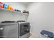 Laundry room with modern washer and dryer, complemented by storage shelves, combines functionality and convenience at 7749 W Florence Ave, Phoenix, AZ 85043