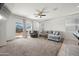 Spacious living room with plush sofa, sliding glass door access to the backyard, ceiling fan, and neutral carpet at 7749 W Florence Ave, Phoenix, AZ 85043