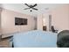 Bright bedroom with a ceiling fan, TV, and adjacent bathroom enhances relaxation and convenience at 7749 W Florence Ave, Phoenix, AZ 85043