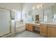 Bright bathroom featuring double sinks, a large mirror, glass-enclosed shower and soaking tub at 9142 E La Posada Ct, Scottsdale, AZ 85255