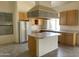 A spacious open kitchen featuring light wood cabinets, an island, a cooktop and a range hood at 9142 E La Posada Ct, Scottsdale, AZ 85255