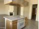 View of kitchen island with cooktop and oven, with view to dining area, fireplace, and front door at 9142 E La Posada Ct, Scottsdale, AZ 85255