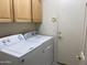 Laundry room featuring a washer and dryer, wooden cabinets, and a white door at 9142 E La Posada Ct, Scottsdale, AZ 85255