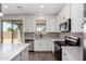Well-lit kitchen boasts stainless steel appliances, quartz countertops, and sleek white cabinets at 11627 W Green Dr, Youngtown, AZ 85363