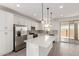 Bright kitchen featuring white cabinetry, stainless steel appliances, a large island, and sliding glass doors to the backyard at 11631 W Green Dr, Youngtown, AZ 85363