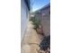 Narrow side yard features a concrete path, block wall, AC Unit, and mature landscaping for added privacy at 13001 W Aster Dr, El Mirage, AZ 85335