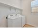 A bright laundry room features a window, overhead shelving and a side by side washer and dryer at 13448 W Auburn Dr, Peoria, AZ 85383