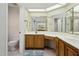 Bathroom with tile floor, a toilet and vanity with white countertop, wood cabinets, and a large mirror at 14111 W Cavalcade Dr, Sun City West, AZ 85375