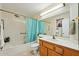 Bright bathroom featuring a tub/shower with a blue curtain and a wood vanity with a white countertop at 14111 W Cavalcade Dr, Sun City West, AZ 85375