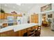 Bright kitchen with skylight features wooden cabinets, white appliances, breakfast bar, and adjacent living area at 14111 W Cavalcade Dr, Sun City West, AZ 85375