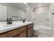 Bathroom featuring double sink vanity with granite countertop and tub with white tiled walls at 15586 S 181St Dr, Goodyear, AZ 85338