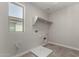 Laundry room includes tile flooring, shelf, utility connections, and natural light from a window at 15586 S 181St Dr, Goodyear, AZ 85338