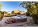 Beautiful backyard with a custom stone hot tub, lush landscaping, and private setting at 17466 N 64Th Ave, Glendale, AZ 85308