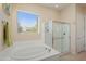 Bathroom featuring a large soaking tub next to a glass shower, and window at 20453 N 264Th Ave, Buckeye, AZ 85396
