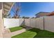 Enclosed backyard featuring a block wall, a narrow strip of artificial grass, and a concrete pathway at 2828 E Waltann Ln # 1, Phoenix, AZ 85032