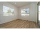 Bright bedroom with wood look ceramic tile flooring, two large windows and white walls at 40165 N Alameda Dr, San Tan Valley, AZ 85140