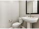 A well-lit powder room with pedestal sink, modern faucet, mirror, and toilet at 5850 E Ringtail Way, Phoenix, AZ 85054