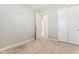 A neutral carpeted bedroom boasts two white doors, baseboards, and a fresh coat of paint at 5850 E Ringtail Way, Phoenix, AZ 85054