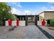 Well-maintained home with a gated front entry, black and white exterior, colorful planters, decorative rocks, and paver walkway at 7042 N 12Th Way, Phoenix, AZ 85020