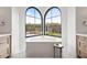 Bright bathroom featuring a modern soaking tub set under arched windows with a view of the landscape at 7157 E Bronco Dr, Paradise Valley, AZ 85253