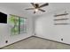 Cozy bedroom includes a ceiling fan, neutral carpet, a window view, and floating shelves at 8049 E Des Moines St, Mesa, AZ 85207