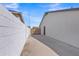 Long driveway secured by a black iron gate between two white stucco home exteriors at 8049 E Des Moines St, Mesa, AZ 85207