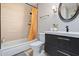 Well-lit bathroom with modern vanity, round mirror, and tub with bright patterned shower curtain at 8213 E Whitton Ave, Scottsdale, AZ 85251