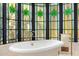 Close-up of a bathtub beneath a stained glass window with ornate design and brass fixtures at 8712 N 64Th Pl, Paradise Valley, AZ 85253