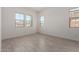 An empty bedroom featuring ceramic tile floors and natural light from three windows at 12029 W Marguerite Ave, Avondale, AZ 85323