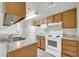 Well-lit kitchen featuring matching wood cabinets, white appliances, and laminate countertops at 12123 W Bell Rd # 241, Surprise, AZ 85378