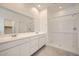 Bright bathroom featuring a double vanity, large mirror, and walk-in shower at 15065 W Hackamore Dr, Surprise, AZ 85387