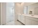 Modern bathroom with a double vanity, neutral tile, and doorway to the bedroom at 15065 W Hackamore Dr, Surprise, AZ 85387