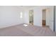 A bright main bedroom featuring neutral carpet, white walls, and a doorway to the en-suite bathroom at 1892 E Empeltre Rd, San Tan Valley, AZ 85140