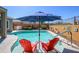 Inviting pool area features a sun umbrella, red chairs and well-manicured landscaping creating a peaceful retreat at 19672 N 260Th Ave, Buckeye, AZ 85396