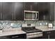 Close up of kitchen with stainless steel appliances, stylish backsplash, and sleek dark cabinetry at 23800 N 169Th Ave, Surprise, AZ 85387