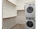 Laundry room with stacked washer and dryer and open shelving for efficient storage at 23800 N 169Th Ave, Surprise, AZ 85387