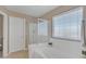 Bright bathroom featuring a glass shower, soaking tub, and natural light from the window at 25038 W Rancho Vista Dr, Buckeye, AZ 85326