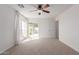 Bright bedroom features neutral carpet, ceiling fan, and sliding glass door to patio at 405 E Wescott Dr, Phoenix, AZ 85024