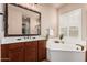 Relaxing bathroom showcasing a soaking tub, dual sink vanity, and plantation shutters for natural light at 4318 N 180Th Dr, Goodyear, AZ 85395