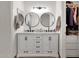 Bathroom featuring a dual sink vanity with round mirrors, cabinet and closet with clothes at 5258 E Elena Ave, Mesa, AZ 85206