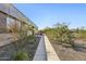 Walking path alongside a building with community pool in the background and native landscaping at 5848 E Covey Ln, Phoenix, AZ 85054