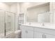 Bright bathroom with double sinks, shower, tile floors, and built-in storage shelves at 7456 N 126Th Ln, Glendale, AZ 85307
