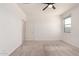 Bright bedroom with a ceiling fan, window, carpet floors, and a white door at 7456 N 126Th Ln, Glendale, AZ 85307