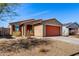 Single-story house featuring a desert landscape, a red garage door, and a cozy entrance at 7456 N 126Th Ln, Glendale, AZ 85307