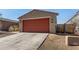 Cozy single-story home featuring a red garage door and a concrete driveway at 7456 N 126Th Ln, Glendale, AZ 85307