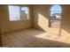 A bright, empty bedroom features tiled floors, light walls, and a large window, perfect for customization at 8640 S 16Th Pl, Phoenix, AZ 85042