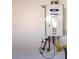 Image of a Brewer Rinnai brand water heater installed on a plain, white wall with electrical outlet nearby at 10039 W Verde Ln, Avondale, AZ 85392