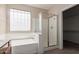 Bathroom featuring a glass enclosed shower, garden tub, and natural light from the window at 10287 S 175Th Ave, Goodyear, AZ 85338