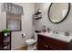 Well-lit bathroom with modern fixtures, dark wood vanity, decorative accents, and a round mirror at 11872 W Sherman St, Avondale, AZ 85323